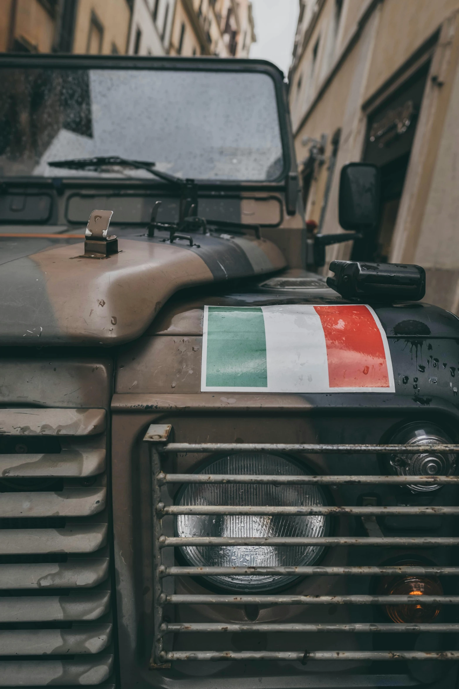 a military vehicle parked on the side of a street, an album cover, by Alessandro Allori, pexels contest winner, renaissance, italian flag, close up shot a rugged, profile image, ireland