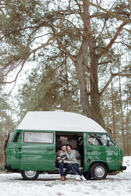 a couple sitting in the back of a green van in the snow, by Grytė Pintukaitė, pexels contest winner, renaissance, standing in the forrest, square, springtime, low quality photo