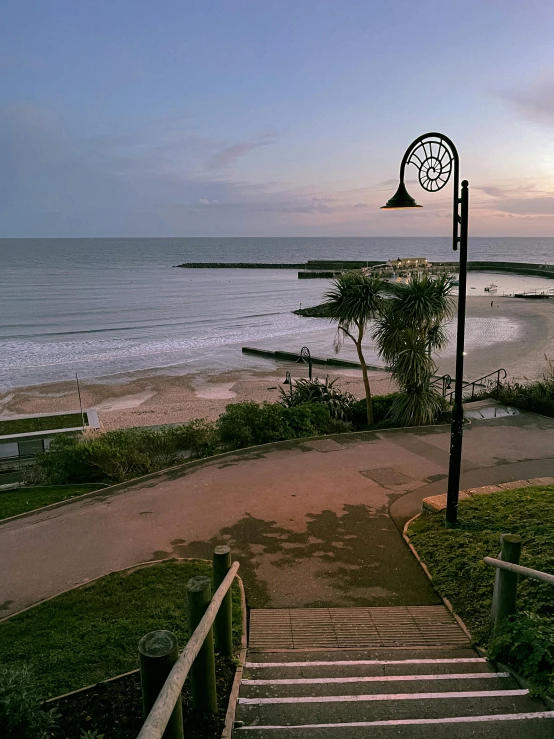 a set of stairs leading down to the beach, a picture, happening, lamp posts, soft lighting from above, conor walton, early evening