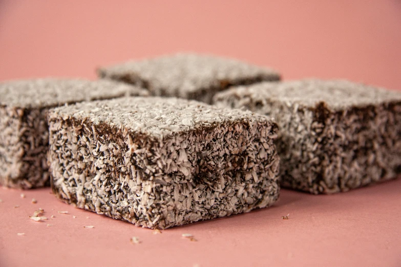 a pile of brownies sitting on top of a pink surface, hurufiyya, grey, detailed product image, medium-shot, crackles