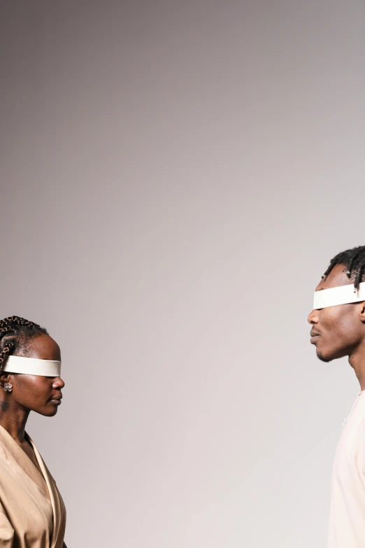 two people with blindfolds standing next to each other, by Nina Hamnett, afrofuturism, eyes in different directions, model, bandage, they reach into his mind