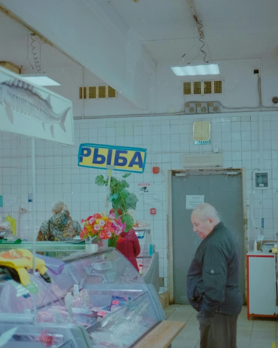a man standing in front of a counter in a store, by Attila Meszlenyi, fish market, alina ivanchenko, sovietwave aesthetic, ( ( theatrical ) )