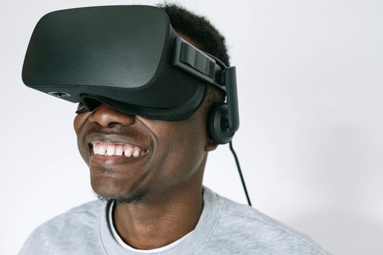 a man wearing a virtual reality headset, by James Morris, trending on unsplash, afrofuturism, brown skin man with a giant grin, 2020 video game screenshot, on grey background, oculus rift