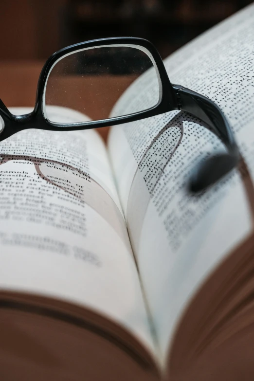 a pair of glasses sitting on top of an open book, up-close, an open book, clearly defined outlines, medium close up