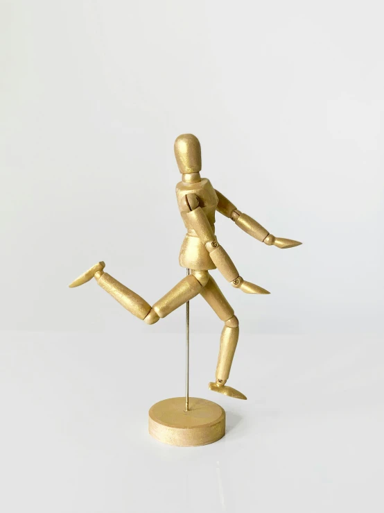 a wooden mannequin on a stand on a white surface, by Arabella Rankin, celebrate goal, gold metal, running pose, 12in action figure