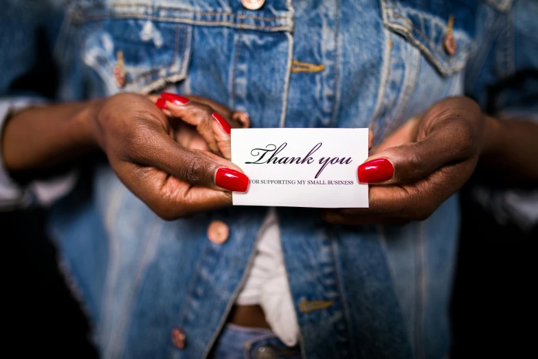 a woman holding a card that says thank you, pexels contest winner, virgil abloh, small in size, maria borges, label