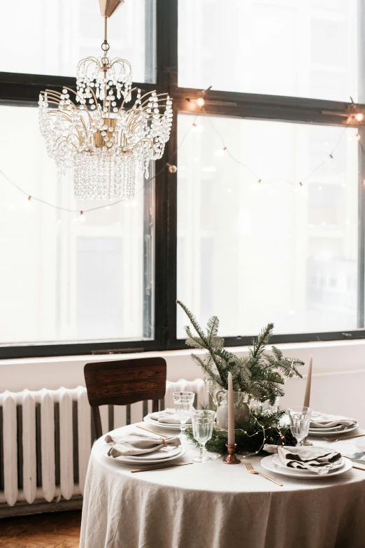 a dining room with a table and a chandelier, by Robbie Trevino, trending on unsplash, tall windows lit up, holiday vibe, white backdrop, place setting