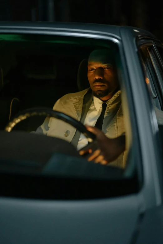 a man sitting in the driver's seat of a car, inspired by Gordon Parks, photorealism, promo still, busy night, black man, cold scene