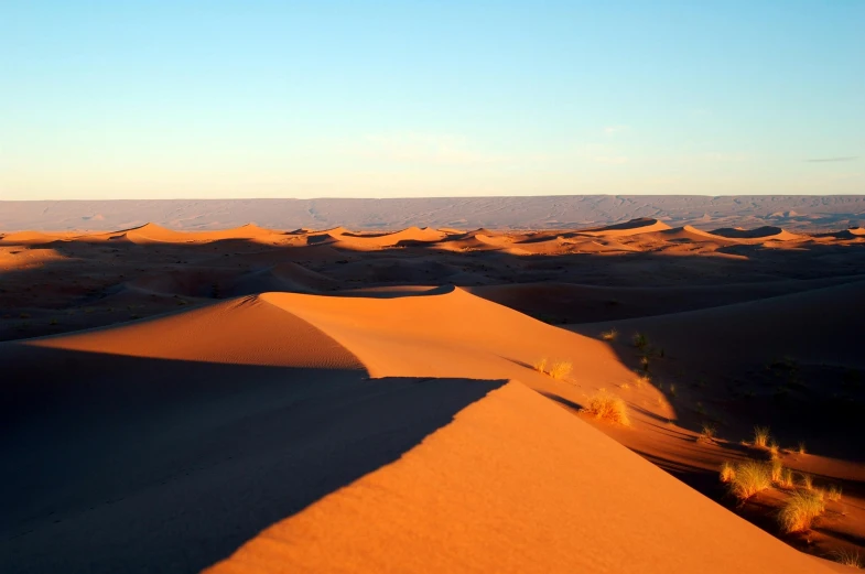 a large sand dune in the middle of a desert, pexels contest winner, les nabis, orange glow, overview, late afternoon, orange and blue sky