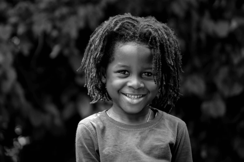 a black and white photo of a little girl smiling, by John Hutton, dreadlock breed hair, by greg rutkowski, boy has short black hair, emmanuel shiru