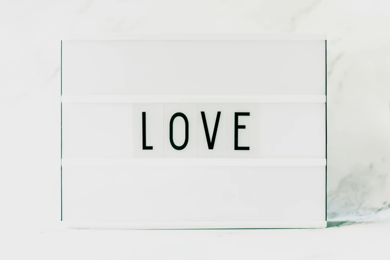 a white lightbox with the word love written on it, minimal palette, white panels, text, looking straight