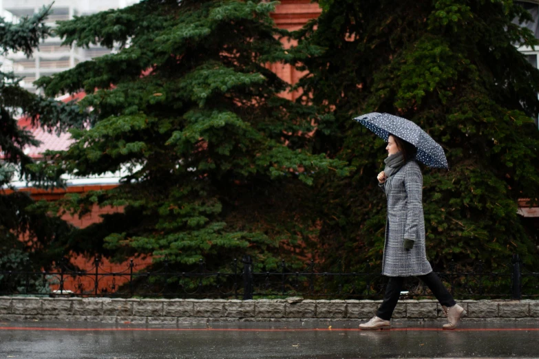 a woman walking in the rain with an umbrella, by Maksimilijan Vanka, unsplash, moscow, dressed in a gray, 15081959 21121991 01012000 4k, cold sunny weather