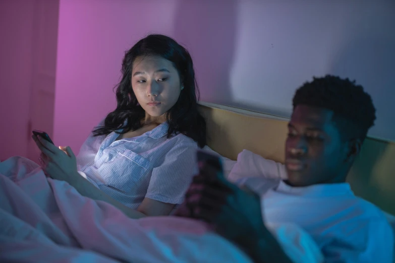 a man and a woman laying in bed looking at a cell phone, trending on pexels, happening, pink and blue lighting, asian descent, looking threatening, black teenage girl