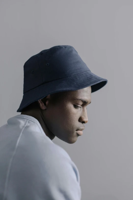 a close up of a person wearing a hat, an album cover, inspired by Paul Georges, unsplash, hyperrealism, wearing a navy blue utility cap, dark skin tone, photographed for reuters, bucket hat