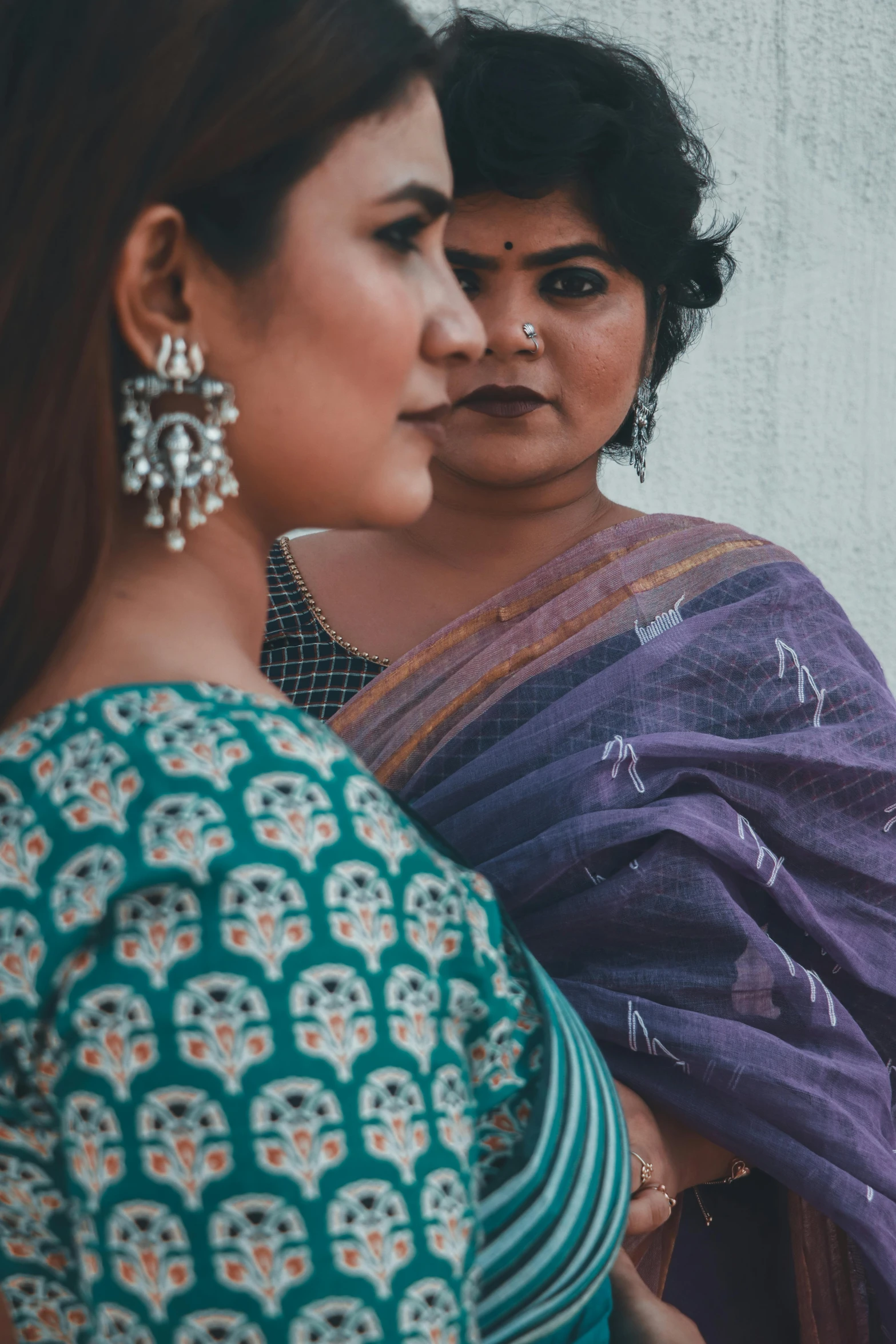 a couple of women standing next to each other, pexels contest winner, wearing a sari, profile image, promotional image, serious expression