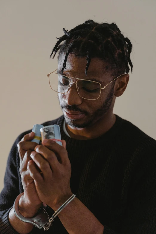 a man wearing glasses looking at his cell phone, an album cover, inspired by Terrell James, trending on pexels, visual art, ashteroth, chewing on a video card, praying with tobacco, handsome man