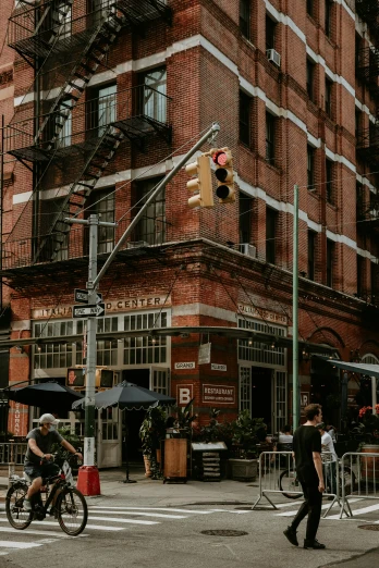 a group of people walking across a street next to a tall building, fire escapes, coffee shop, industrial aesthetic, abcdefghijklmnopqrstuvwxyz