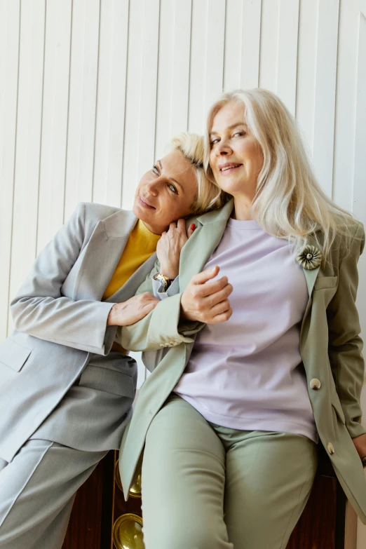 a couple of older women sitting next to each other, trending on pexels, tailored clothing, non binary model, embracing, relaxed dwarf with white hair