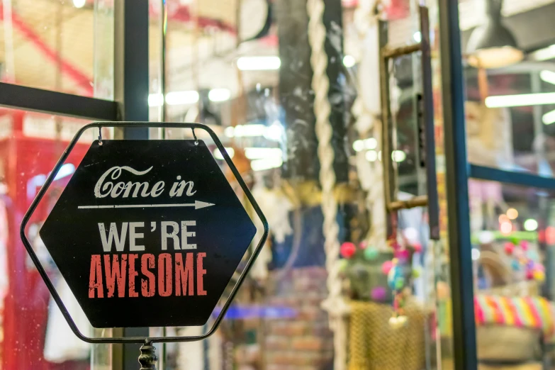 a sign that says, come in we're awesome, by Bernie D’Andrea, trending on unsplash, inside an old magical sweet shop, 💋 💄 👠 👗, crafts and souvenirs, thumbnail
