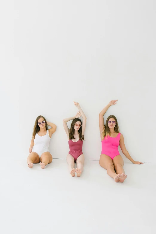 a group of women sitting on top of a white floor, inspired by Ren Hang, unsplash, aestheticism, leotard, brunette, shades of pink, three head one body