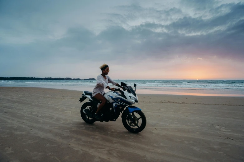 a man riding a motorcycle on top of a sandy beach, in the evening, australian beach, profile image, female beauty