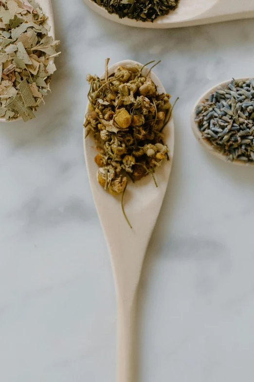 a table topped with wooden spoons filled with different types of herbs, a portrait, by Jessie Algie, unsplash, renaissance, chamomile, close-up product photo, bath, long shot view