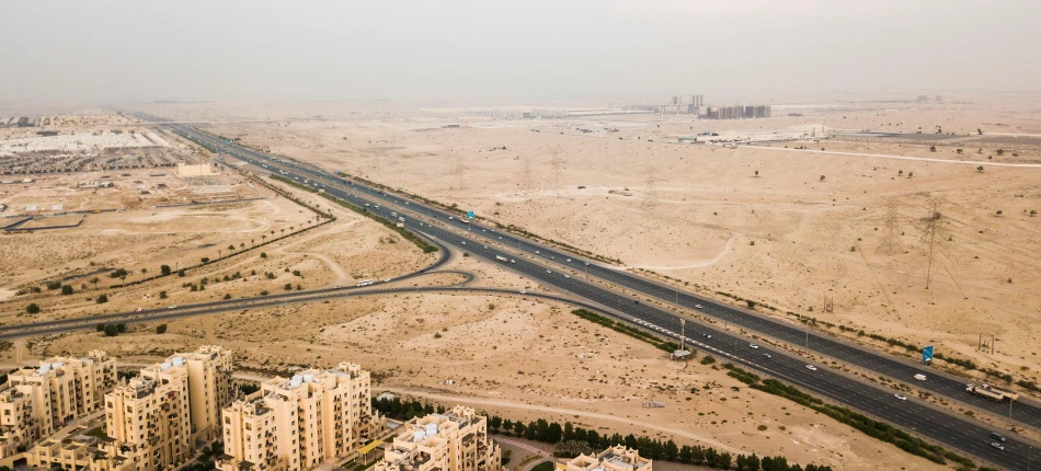 an aerial view of a highway in the middle of a desert, pexels contest winner, hurufiyya, city in the background, ameera al taweel, slight haze, infrastructure