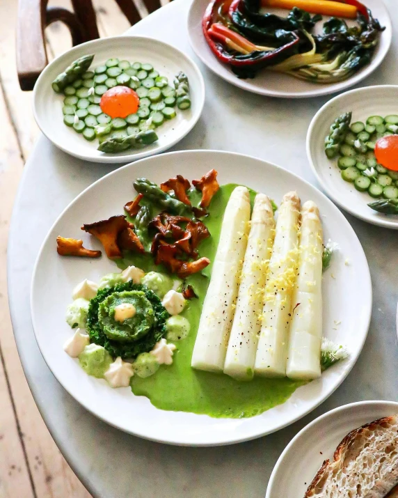 a table topped with plates of food on top of a wooden table, inspired by Géza Dósa, asparagus, pale greens and whites, but futuristic food, instagram picture