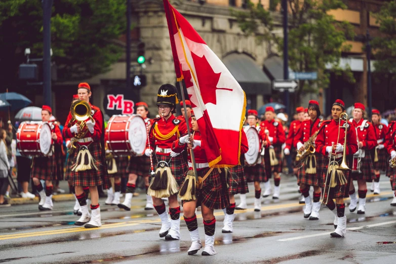 a group of men in kilts marching down a street, an album cover, by Nicolette Macnamara, shutterstock, vancouver school, wearing a red captain's uniform, maple syrup sea, professionally post-processed, concert