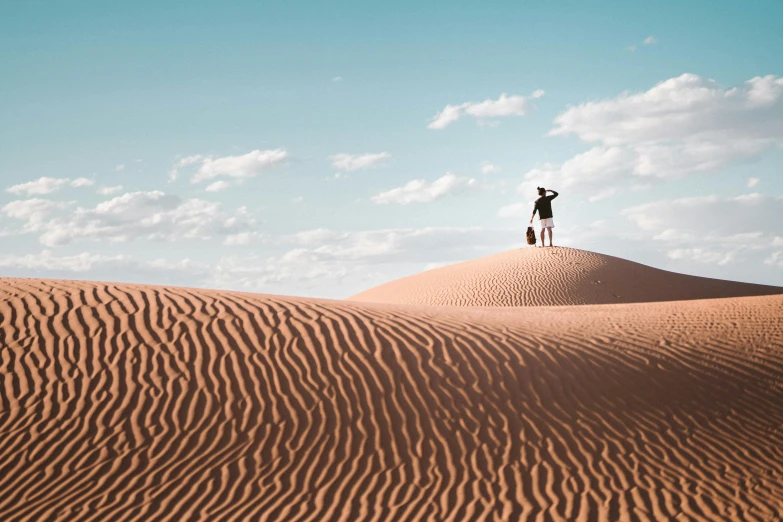 two people standing on top of a sand dune, inspired by Scarlett Hooft Graafland, unsplash contest winner, an arab standing watching over, australian outback, victorian arcs of sand, tiny person watching