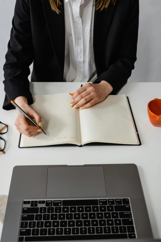 a woman sitting at a desk writing in a notebook, trending on pexels, a man wearing a black jacket, minimalist logo without text, thumbnail, it specialist