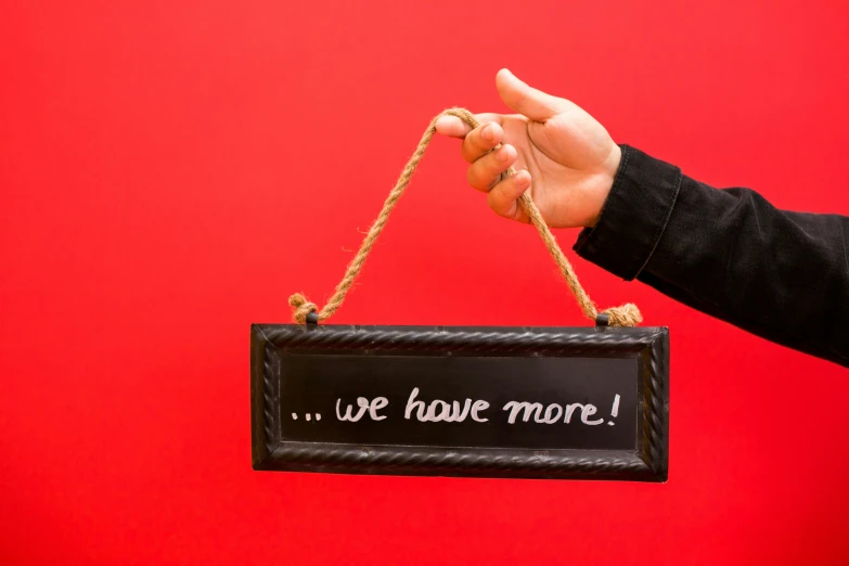 a person holding a sign that says we have more, black steel with red trim, holding gift, thumbnail, hanging