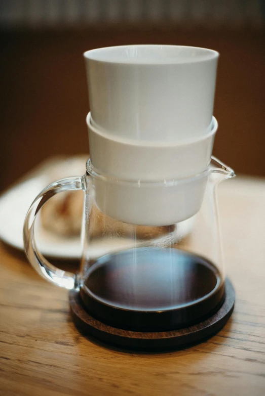 a couple of cups sitting on top of a wooden table, pouring, straining, with a white mug, dissolution filter