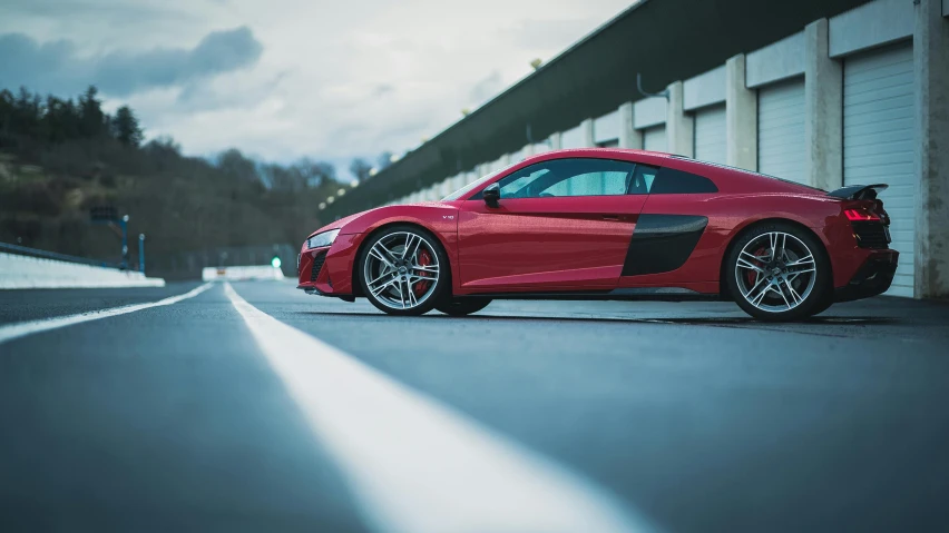 a red sports car parked in front of a building, by Adam Marczyński, pexels contest winner, on a racetrack, from the side, drifting, ground angle