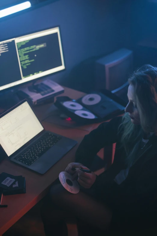 a woman sitting at a desk in front of a computer, hacking effects, threyda, a python programmer's despair, dark setup