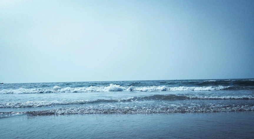 a man riding a surfboard on top of a wave covered beach, unsplash, minimalism, blueish, low quality photo, view from the sea, sparsely populated