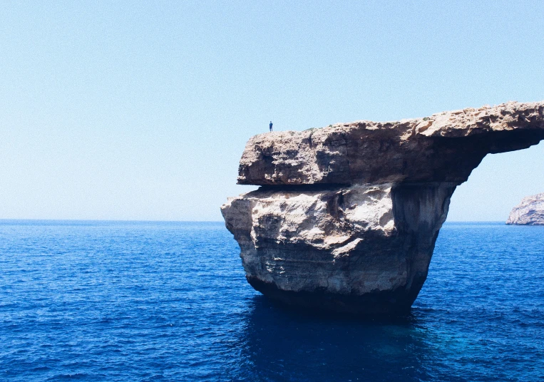 a rock formation in the middle of the ocean, pexels contest winner, minimalism, mediterranean, perched on a rock, half blue, over-shoulder shot