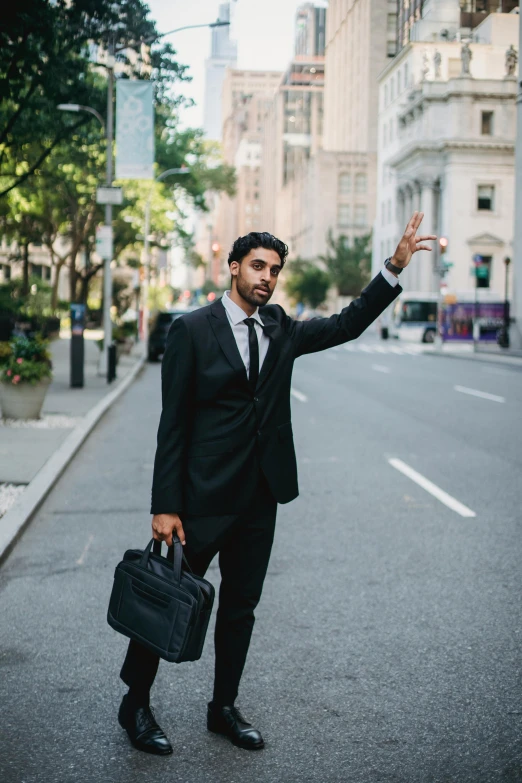 a man in a suit holding a briefcase on a city street, pexels contest winner, renaissance, waving, riyahd cassiem, jen atkin, black tie