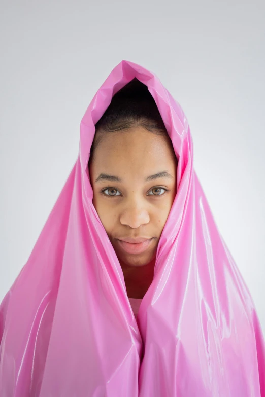 a woman in a pink raincoat covering her face, by Lily Delissa Joseph, tactical poncho latex rags, tessa thompson inspired, resin, inflatable