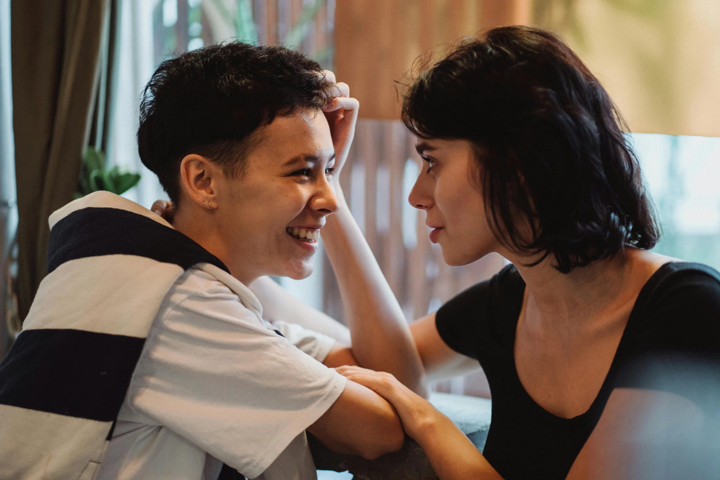 a man and a woman sitting next to each other, trending on pexels, happening, boy has short black hair, head bent back in laughter, lesbian embrace, teenage boy