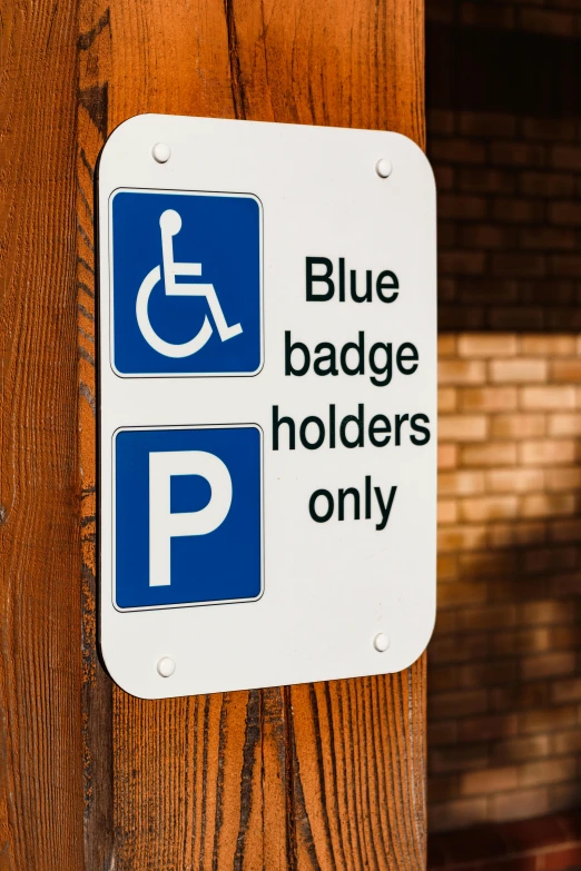 a blue and white sign on a wooden pole, sitting in a wheelchair, badge, blue or red, holographic plastic