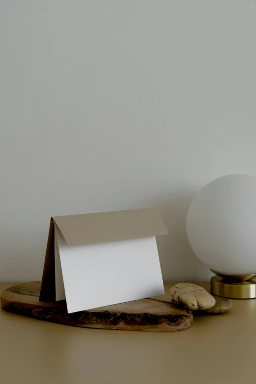 a white lamp sitting on top of a wooden table, card frame, folded, lumi, taupe