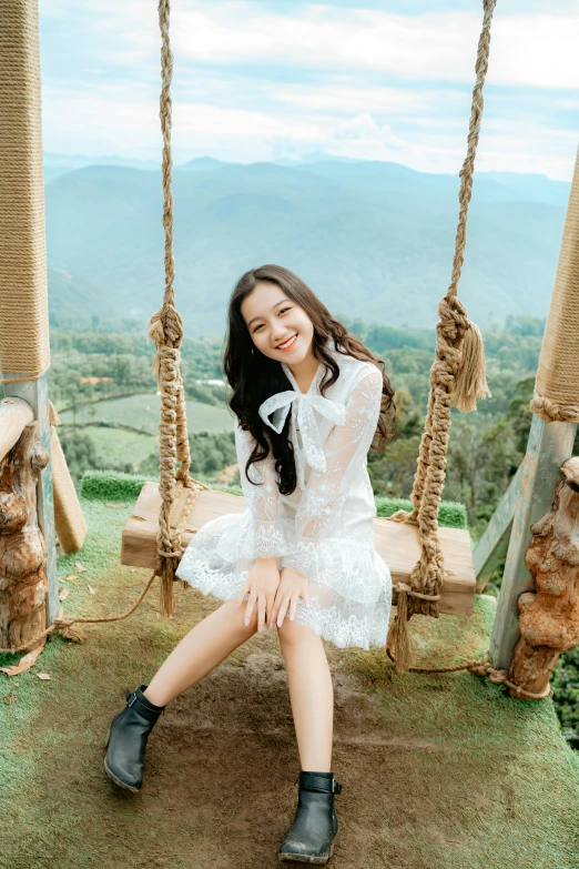 a woman in a white dress sitting on a swing, a picture, inspired by Kim Jeong-hui, pexels contest winner, cute smile, dilraba dilmurat, slide show, in the mountains
