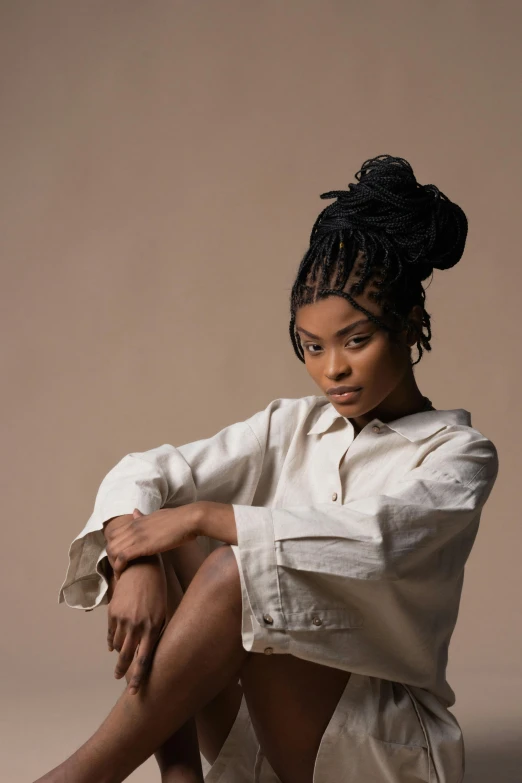 a woman sitting on the ground with her legs crossed, inspired by Esaias Boursse, trending on pexels, renaissance, box braids, plain background, willow smith zendaya, wearing a linen shirt