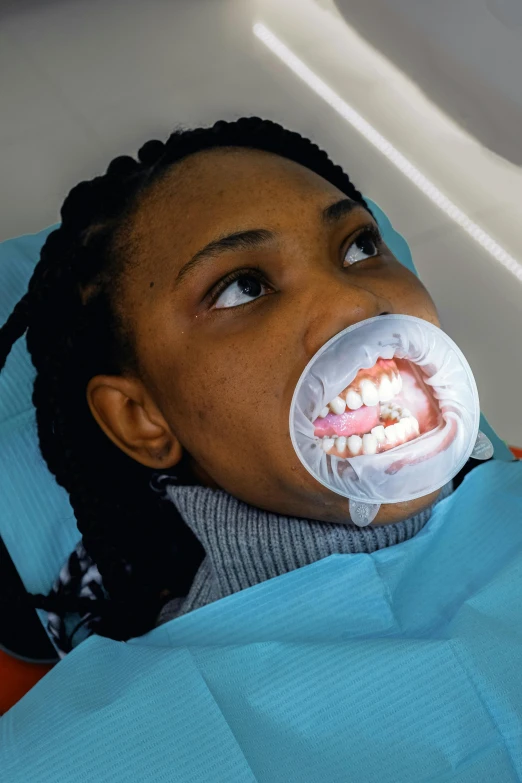 a woman sitting in a chair with a toothbrush in her mouth, a hologram, african facial features, translucent gills, dentist, taken in the late 2000s