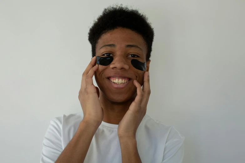 a close up of a person holding a cell phone to their face, large black smile, black eye mask, black teenage boy, photoshoot for skincare brand