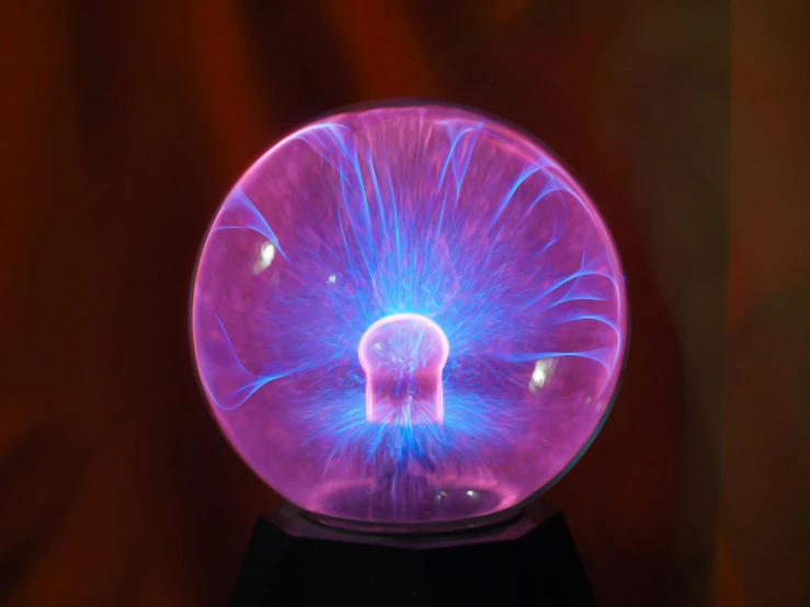 a plasma ball sitting on top of a table, light purple