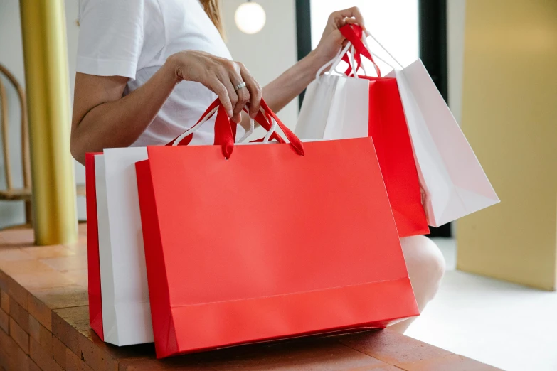 a woman sitting on a bench holding shopping bags, pexels contest winner, happening, white and red color scheme, retail price 4 5 0, rituals, bows