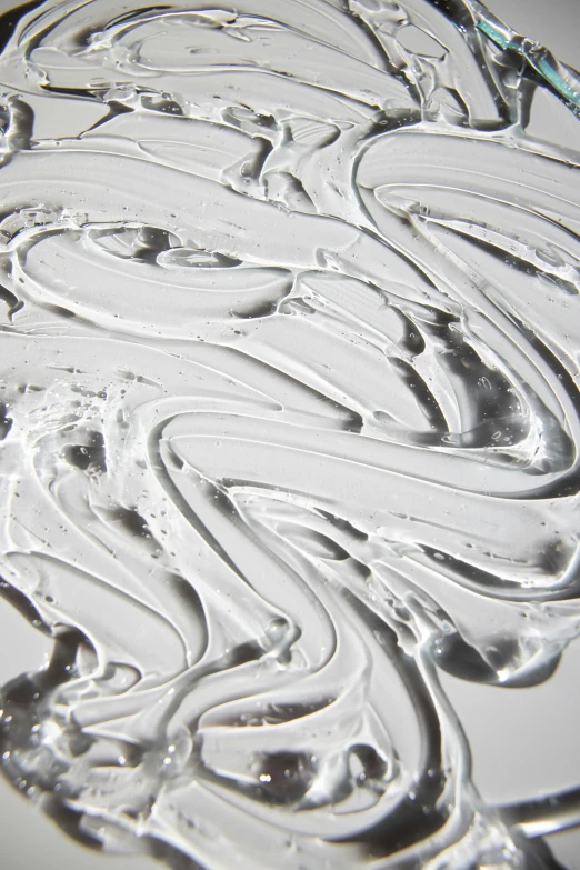 a close up of a plate with frosting on it, inspired by Lucio Fontana, lyrical abstraction, swirly liquid ripples, white and silver, transparent liquid, detailed product shot