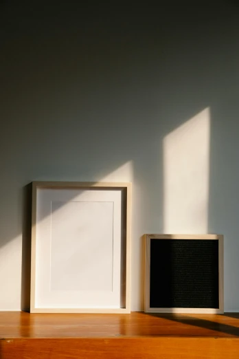 a picture frame sitting on top of a wooden shelf, a minimalist painting, by Harvey Quaytman, unsplash, light and space, two suns, long cast shadows, diptych, back - lit